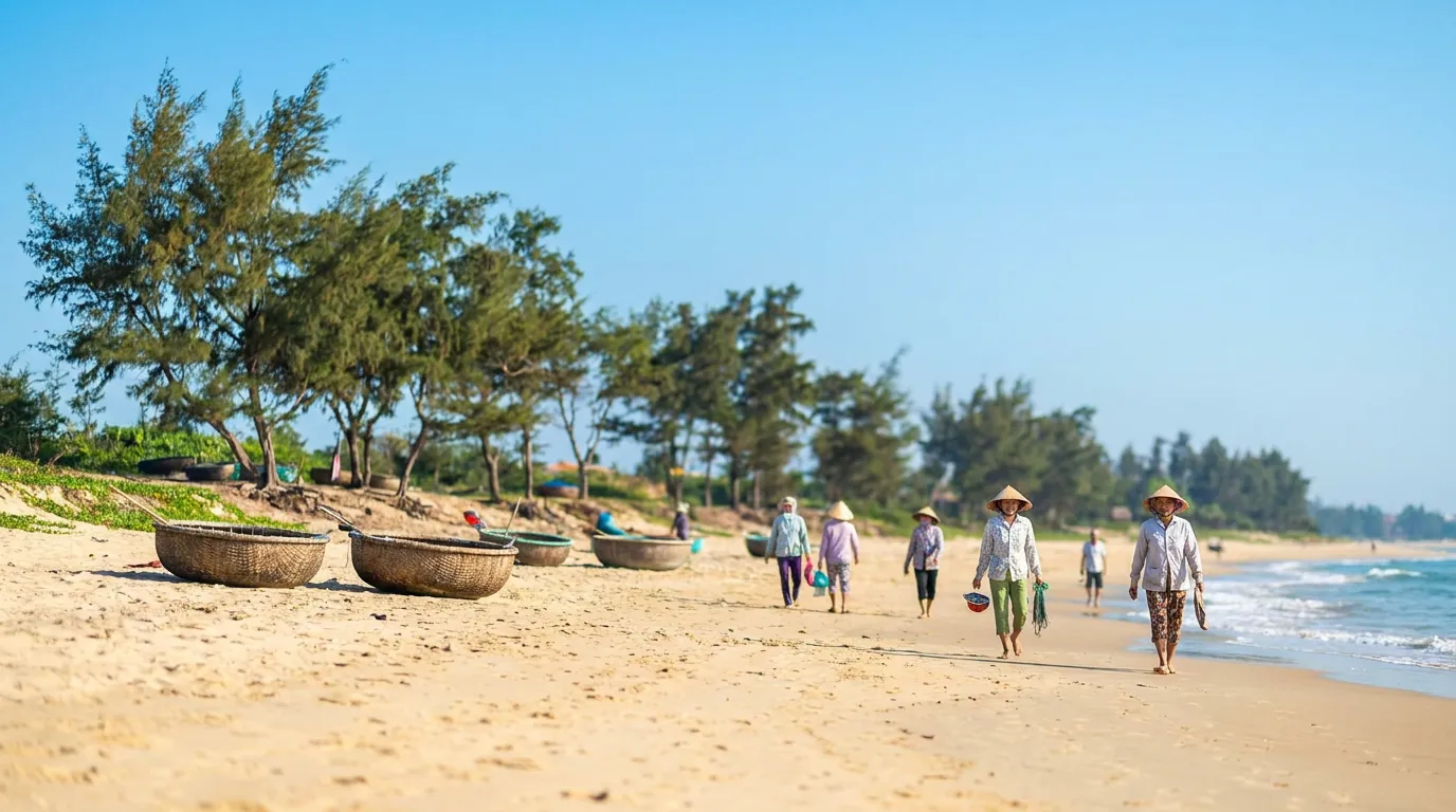 Bãi biển miền Trung buổi sáng sớm mùa hè với người Việt đi dạo trên cát, thuyền thúng nhỏ và hàng phi lao ven bờ, trời trong xanh — ảnh minh họa
