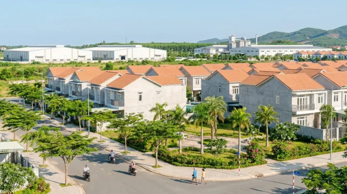 Khu dân cư mới ven khu kinh tế Nam Thanh Hóa với nhà cửa khang trang, cây xanh và đồi phía xa trong nắng sớm — ảnh minh họa